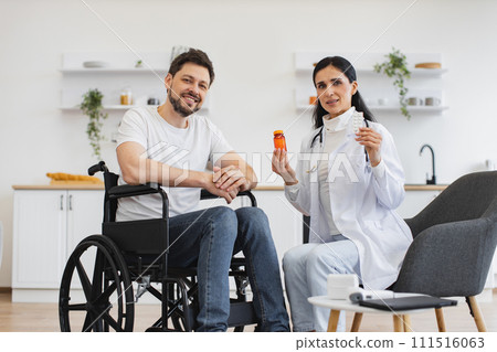 Female therapist with pills on hands consulting mature patient with disability 111516063