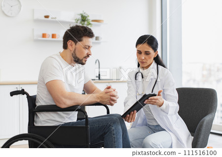 Nurse talking to mature man on wheelchair, showing examination results. Nurse talking to mature man on wheelchair, showing examination results. 111516100