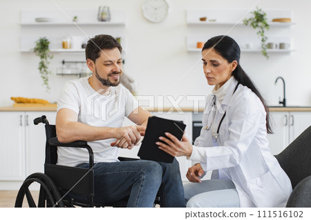 Nurse talking to mature man on wheelchair, showing examination results. 111516102