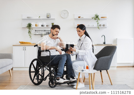 Female brunette doctor checking up condition of bearded male patient at home. 111516278