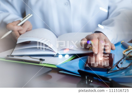 Doctor counts money on phone in office. Doctor counts money on phone in office. 111516725