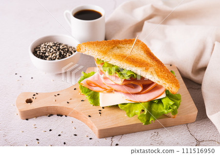 Toast sandwich with ham, cheese and herbs on a wooden board on the table Toast sandwich with ham, cheese and herbs on a wooden board on the table 111516950