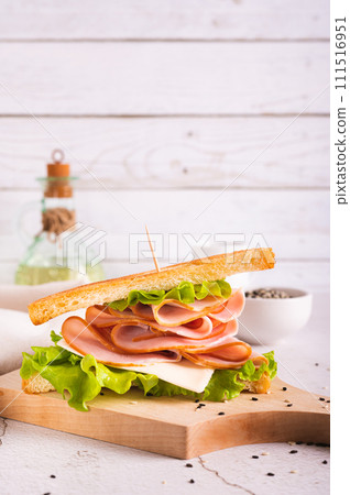 Sandwich with ham, cheese and onion on a wooden board on the table vertical view 111516951