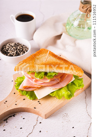 Toast sandwich with ham, cheese and herbs on a wooden board on the table vertical view 111516952