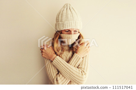 Woman freezing trying to warm up in winter warm knitted clothes, hat and sweater Woman freezing trying to warm up in winter warm knitted clothes, hat and sweater 111517041