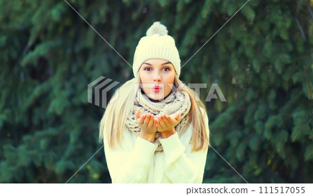 Winter portrait of happy cheerful woman blowing snowflakes from hands in forest on christmas tree 111517055
