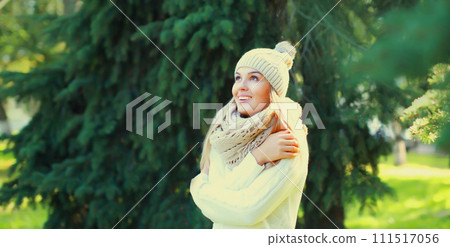 Winter portrait of happy smiling young woman in hat, scarf in forest on christmas tree background 111517056
