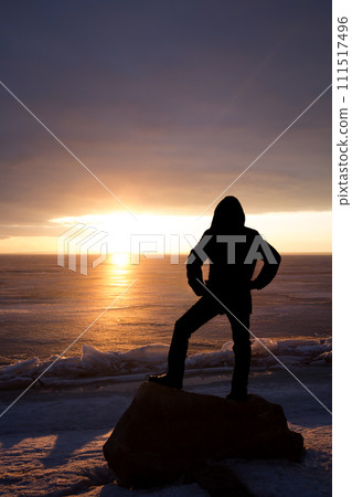 Man on rock on the sea in the ice - silhouette 111517496