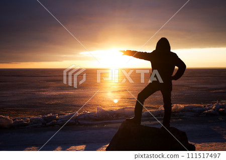 Man on rock on the sea in the ice - silhouette 111517497