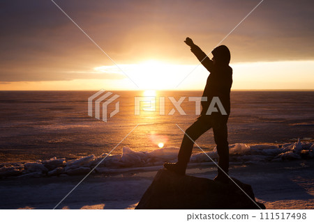 Man on rock on the sea in the ice - silhouette 111517498