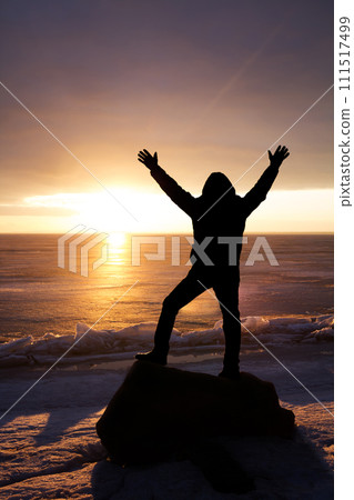 Man on rock on the sea in the ice - silhouette 111517499