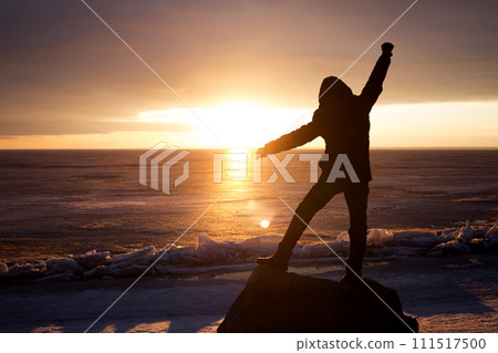 Man on rock on the sea in the ice - silhouette 111517500
