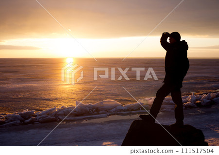 Man on rock on the sea in the ice - silhouette 111517504