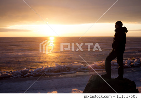 Man on rock on the sea in the ice - silhouette 111517505