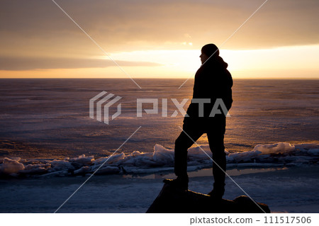 Man on rock on the sea in the ice - silhouette 111517506