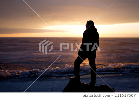 Man on rock on the sea in the ice - silhouette 111517507