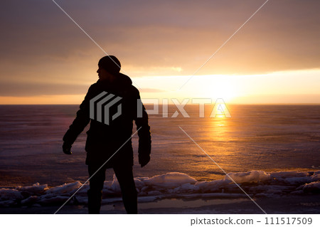 Man on rock on the sea in the ice - silhouette 111517509