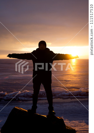 Man on rock on the sea in the ice - silhouette 111517510