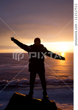 Man on rock on the sea in the ice - silhouette 111517511