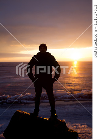 Man on rock on the sea in the ice - silhouette 111517513