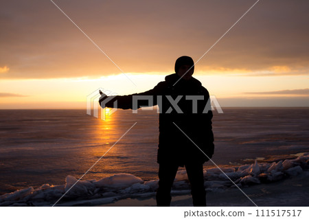 Man on rock on the sea in the ice - silhouette Man on rock on the sea in the ice - silhouette 111517517