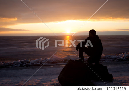 Man on rock on the sea in the ice - silhouette 111517519