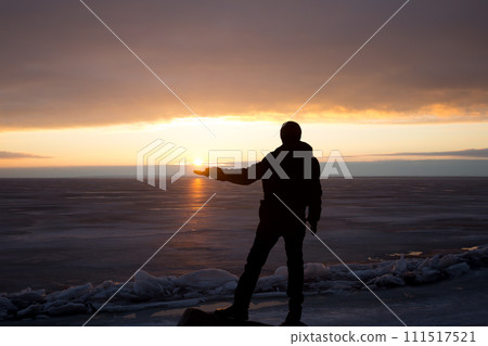 Man on rock on the sea in the ice - silhouette 111517521