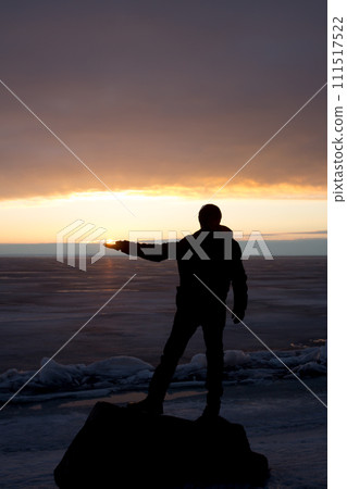 Man on rock on the sea in the ice - silhouette 111517522