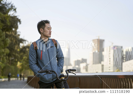young asian man sitting on his bike lost in thought young asian man sitting on his bike lost in thought 111518190