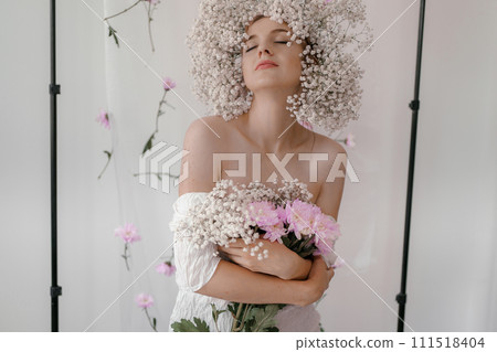 Portrait of sensual blond woman with flowers. Beautiful girl with flowers in her hair. Summer Beauty. Art in a contemporary style. A gypsophila wreath on a white background. Perfume, cosmetics concept 111518404