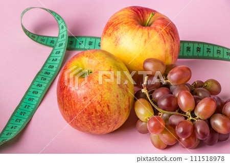 Fresh fruits and measuring tape on a pink background. The concept of diet and healthy eating. 111518978