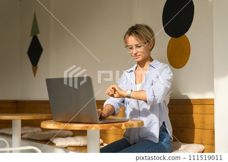 Woman sitting at cafe table and working on laptop computer. Female surfing internet on laptop using Woman sitting at cafe table and working on laptop computer. Female surfing internet on laptop using 111519011