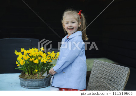 A girl near a pot of daffodils Easter A girl near a pot of daffodils Easter 111519665