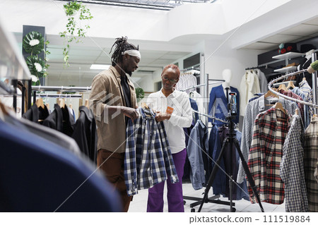 Influencer and shop manager showcasing clothing brand for social media promotion. Blogger and store assistant showing casual shirt and speaking about menswear collection on smartphone camera 111519884