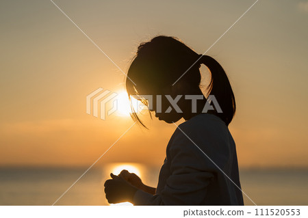 日落時分，一個女孩站在海灘上。 111520553