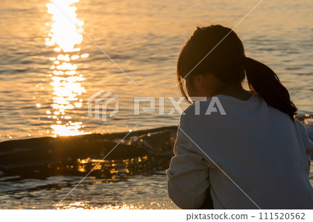 A girl standing on the beach at sunset. 111520562