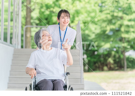 Elderly people in wheelchairs and caregivers (helpers) walking in the park 111521842