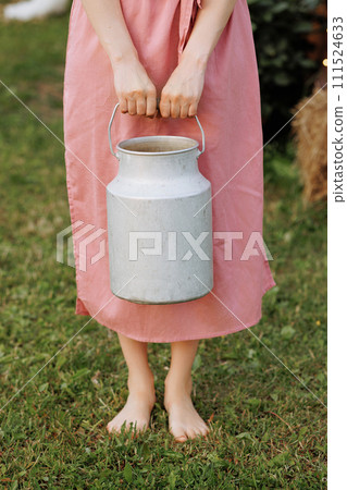 Caucasian woman in pink dress holding milk can 111524633