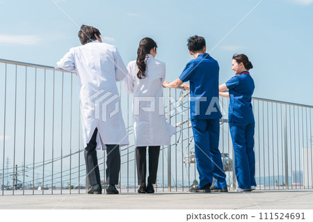 Rear view of male and female doctors, doctors, nurses, medical workers, and technicians spending their break time on the roof of a hospital (4 people) 111524691