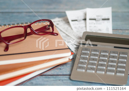 書桌上的收據、眼鏡、計算機和筆記本 書桌上的收據、眼鏡、計算機和筆記本 111525164
