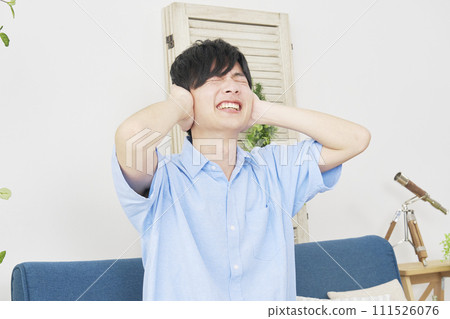 A man covering his ears in the living room A man covering his ears in the living room 111526076