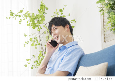 一個男人在客廳用智慧型手機打電話 111526157