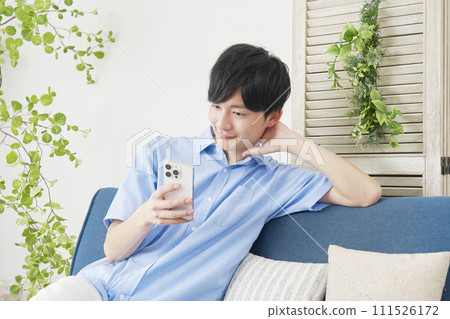 A man who uses smartphones in the living room 111526172