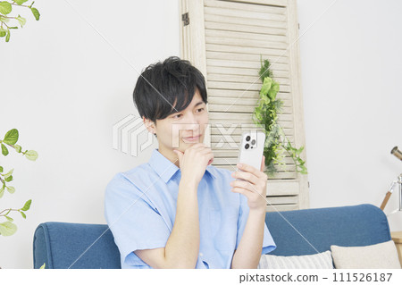 A man using a smartphone while thinking in the living room 111526187
