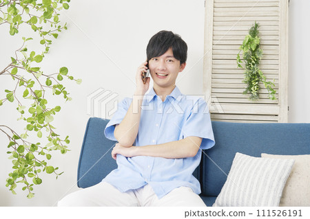 A man calling on a smartphone in the living room, looking at the camera A man calling on a smartphone in the living room, looking at the camera 111526191