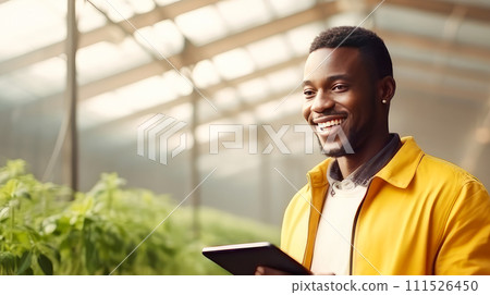 A dark-skinned African American man with a gadget, laptop, tablet is planting and caring for plants, seedlings, vegetables in a greenhouse. A dark-skinned African American man with a gadget, laptop, tablet is planting and caring for plants, seedlings, vegetables in a greenhouse. 111526450
