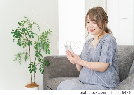 Pregnant woman/maternity/premum using a smartphone on the sofa at home Pregnant woman/maternity/premum using a smartphone on the sofa at home 111526486