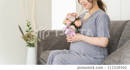 Pregnant woman/maternity sitting on the sofa at home (bouquet/bouquet/maternity photo) 111526502