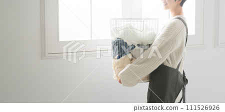 一個女人在背光窗邊拿著衣服,不露面,生活方式家務和清爽的家庭主婦形象 一個女人在背光窗邊拿著衣服,不露面,生活方式家務和清爽的家庭主婦形象 111526926