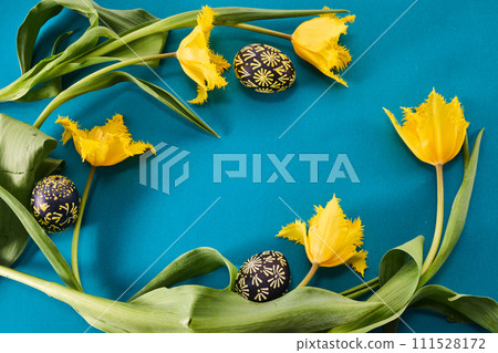Easter spring background. Frame of easter eggs and flowers. Yellow tulips on blue. Easter spring background. Frame of easter eggs and flowers. Yellow tulips on blue. 111528172